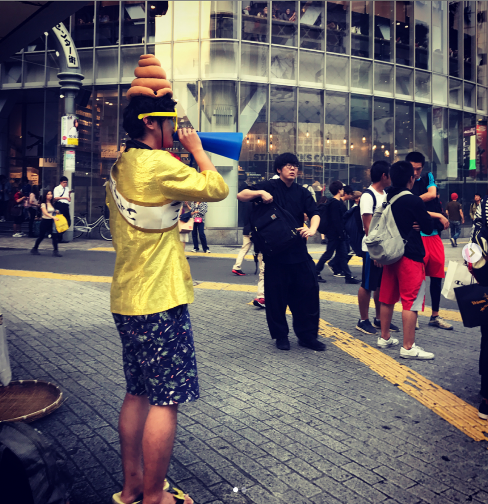 guy broadcasting on microphone wearing poop emoji hat
